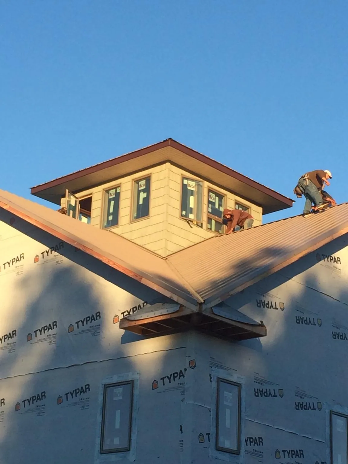 Roofers working around a rooftop cupola on a new metal roof at sunset — Roof Waterproofing in Hume by Roofing Brothers